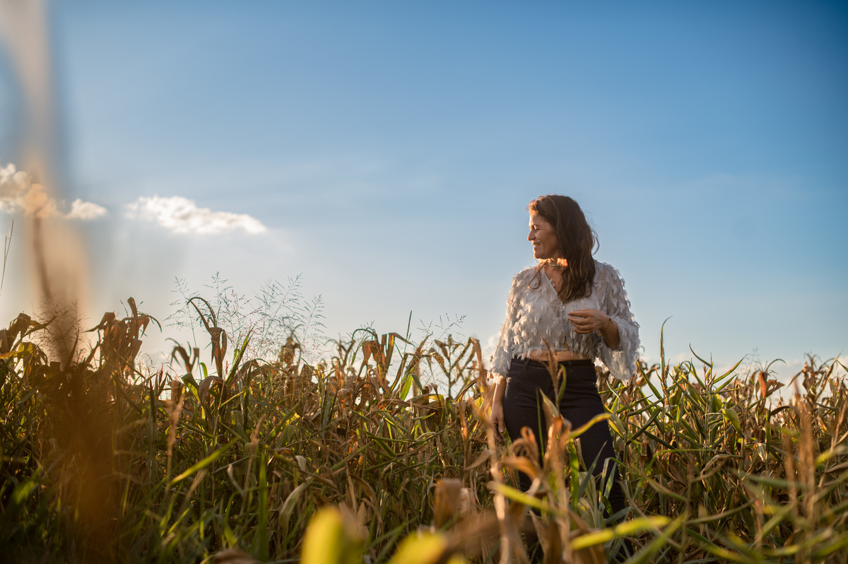 Ensaio feminino no meio de uma plantação de milho, final do dia