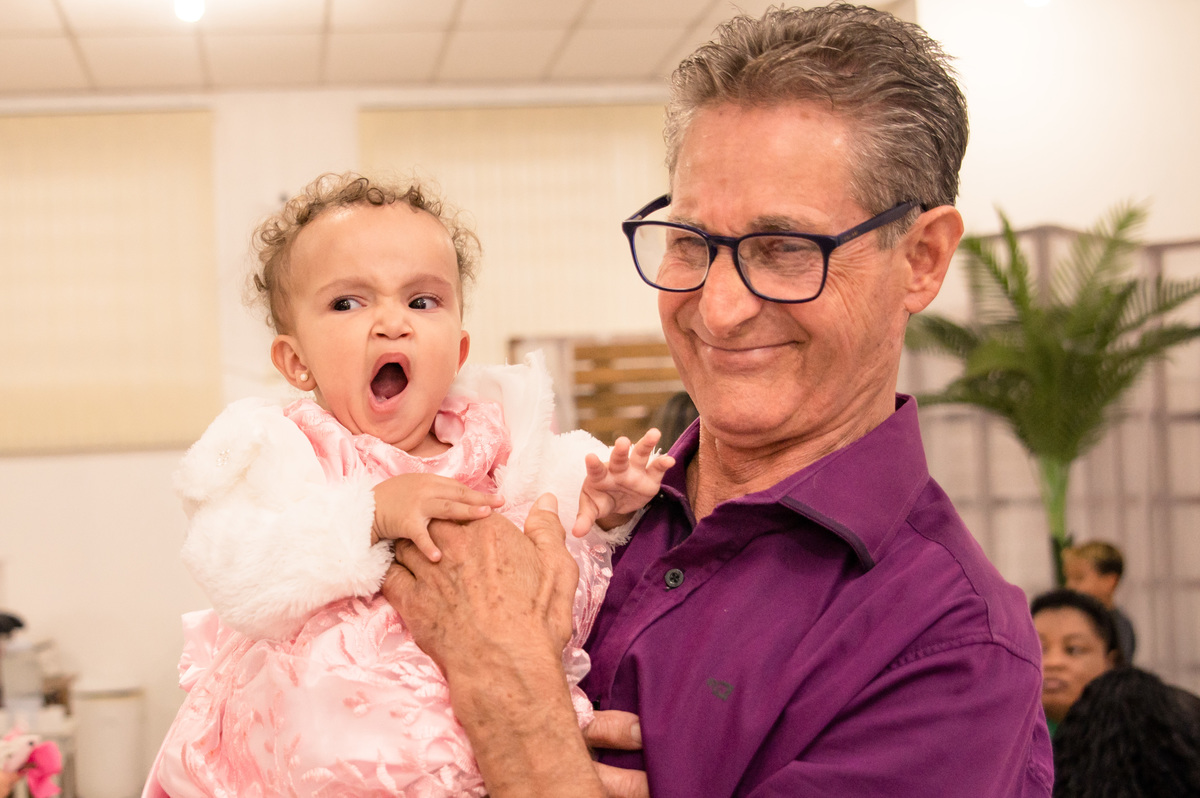 festa de aniversário infantil, menina bocejando no colo do avô, vestida de princesa