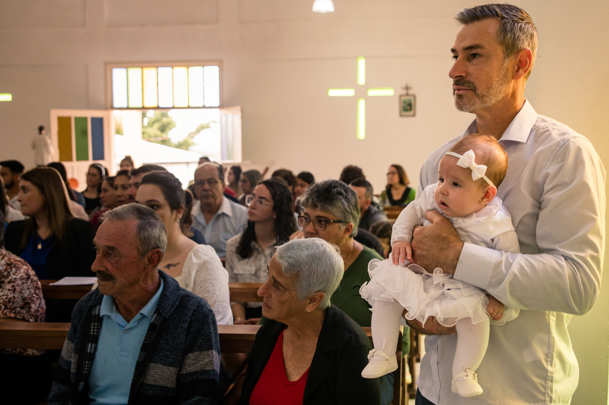 batismo batizado - bebê no colo do pai com a família na missa