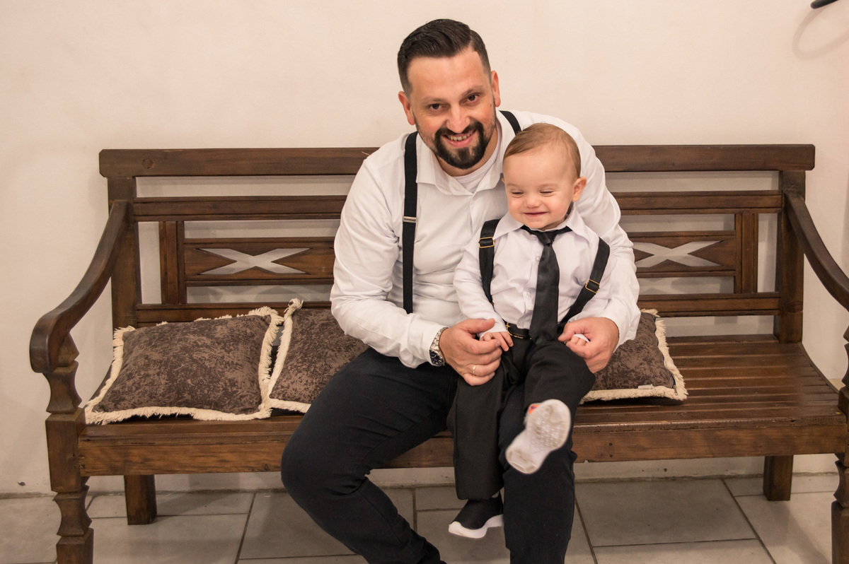 Festa de aniversário infantil - criança de um aninho no colo do pai, mesma roupa