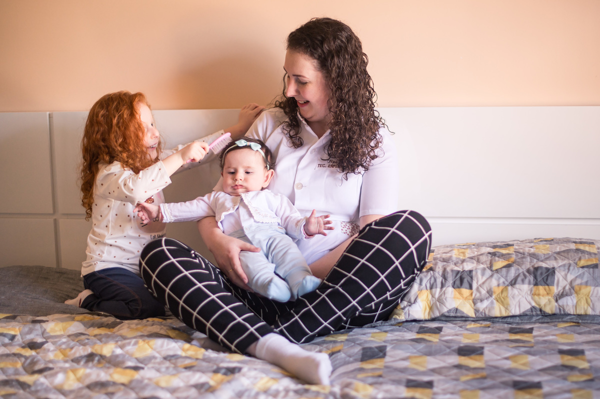 Ensaio de família em casa - irmã mais velha penteando o cabelo do bebê