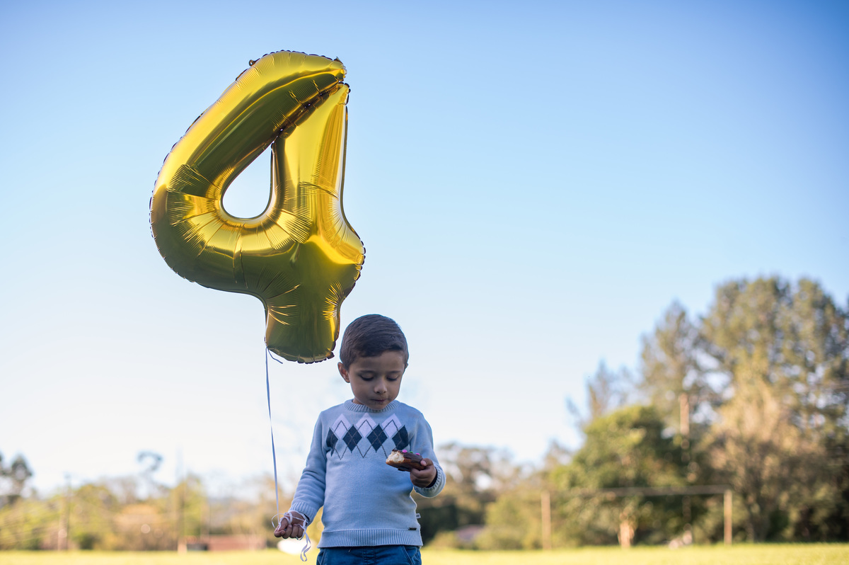 ensaio de família, criança comendo o bolinho com um balão de 4 anos na mão