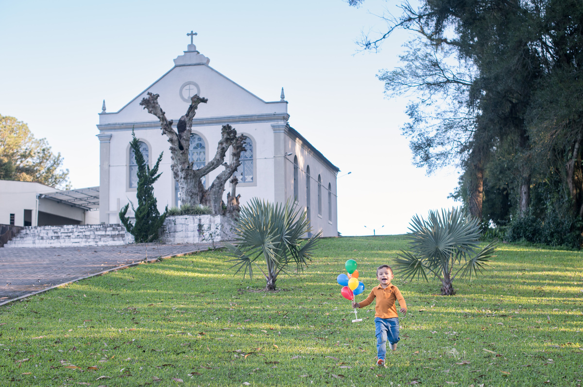 ensaio de família, criança correndo com balões coloridos na mão 