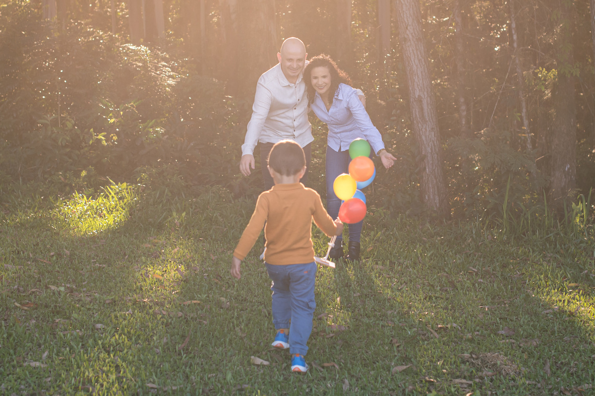 ensaio de família, criança correndo na direção dos pais, luz de flare