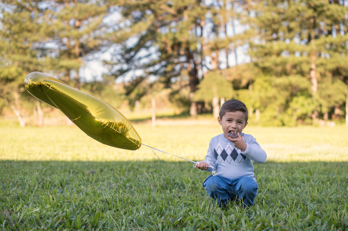 ensaio de família, criança comendo o bolinho com um balão de 4 anos na mão