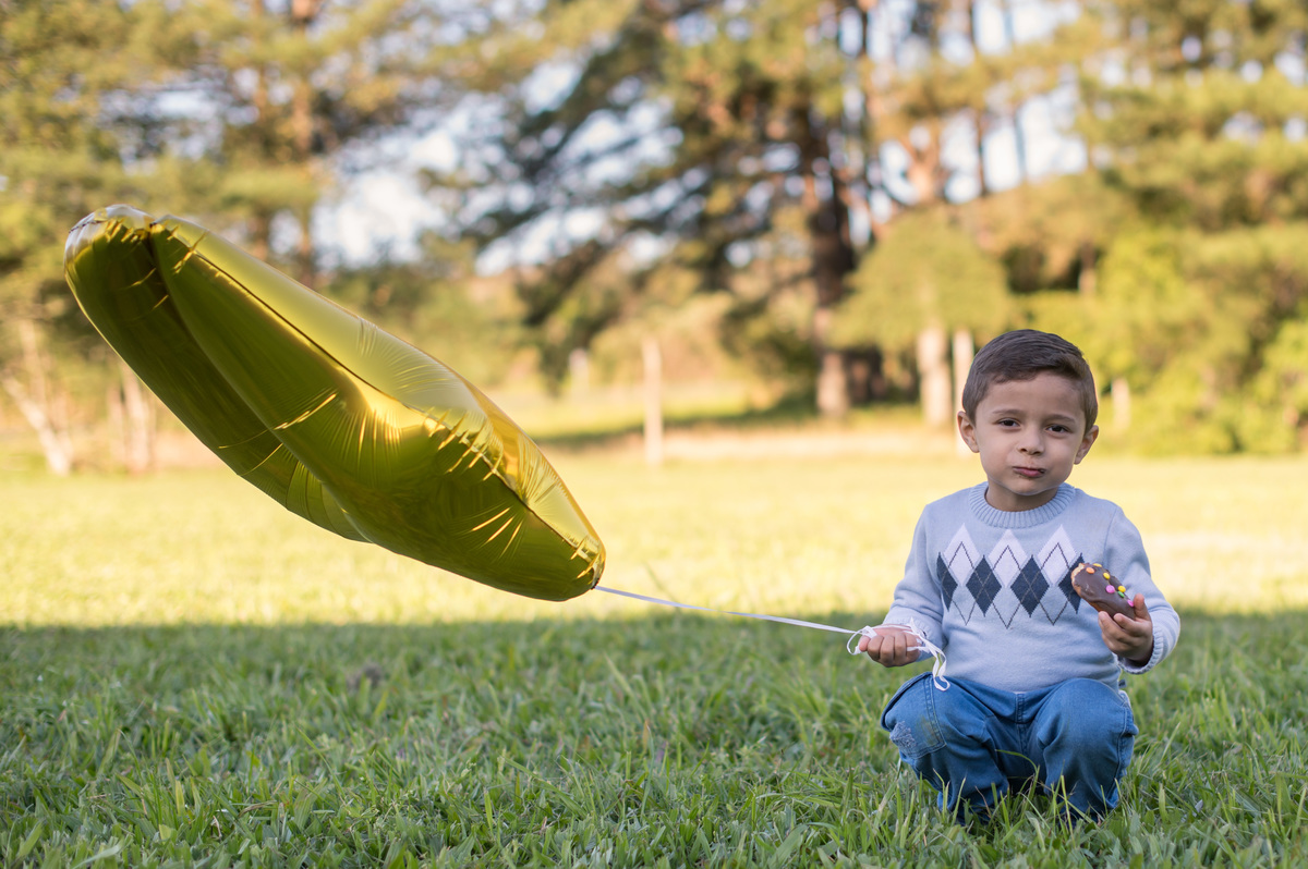 ensaio de família, criança comendo o bolinho com um balão de 4 anos na mão