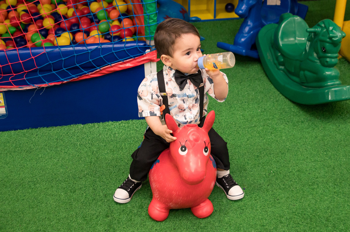 Festa de aniversário infantil - criança tomando suco na mamadeira em brinquedo