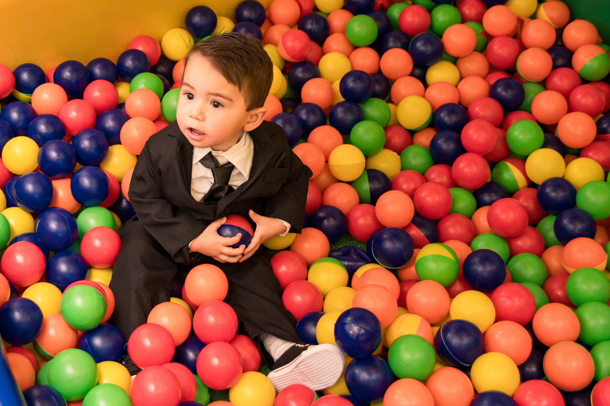 Festa de aniversário infantil - criança com roupa de poderoso chefinho na piscina de bolinhas