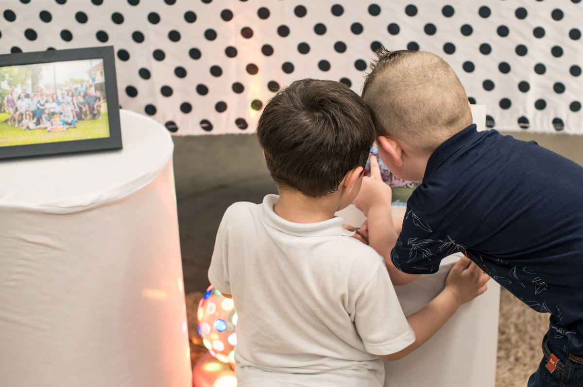 crianças olhando fotos impressas na mesa decorada