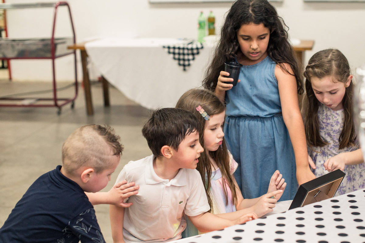 crianças olhando fotos impressas na mesa decorada