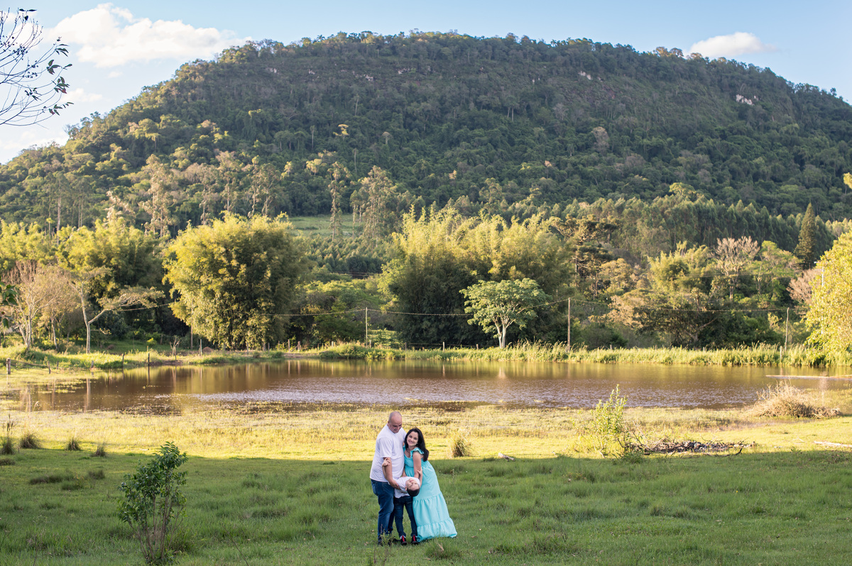 Ensaio de gestante da chácara - foto de família com açude e montanha ao fundo