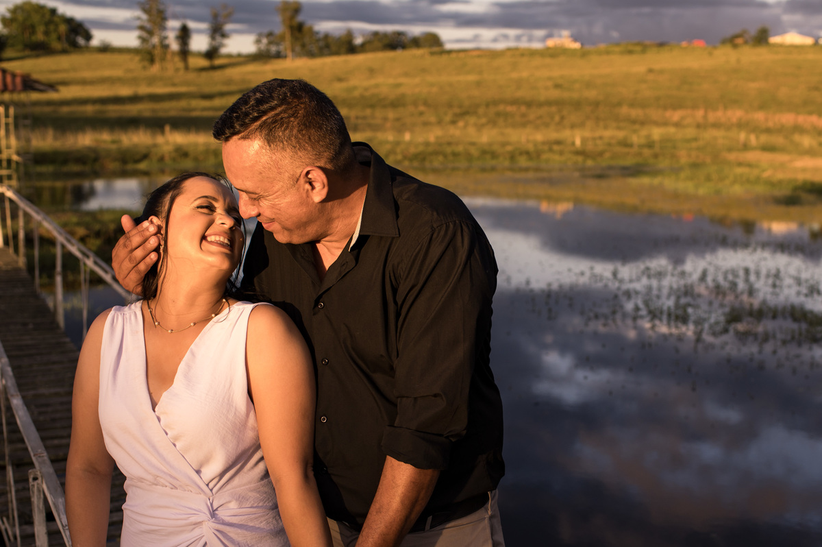 Ensaio externo de casal na chácara, casal na ponte com laguinho, luz dourada do sol à tardinha (golden hour)