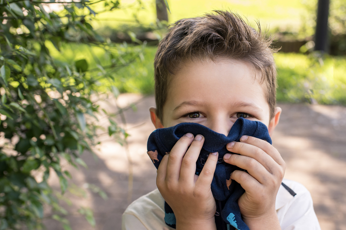 Ensaio de gestante, irmão mais velho cheirando a roupa do bebê