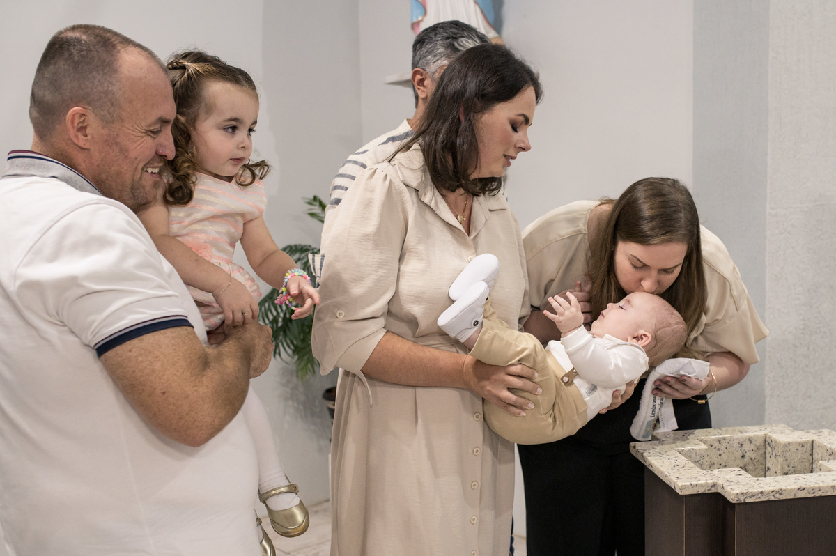 Hora do batizado, dinda beijando a testa do bebê