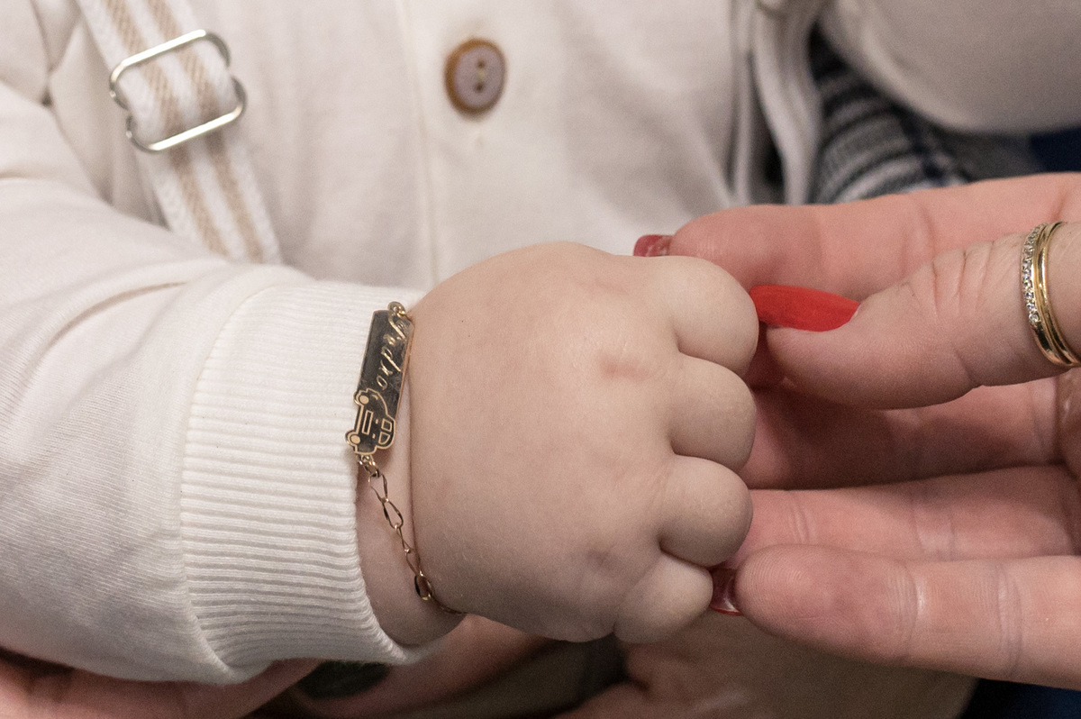 foto da mão do bebê no batizado com uma pulseira e seu nome Pedro