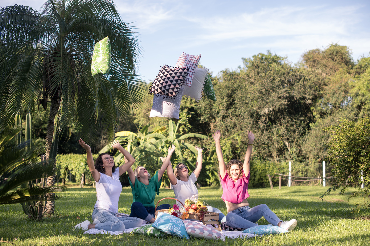 Ensaio externo, amigas jogando almofadas para o alto