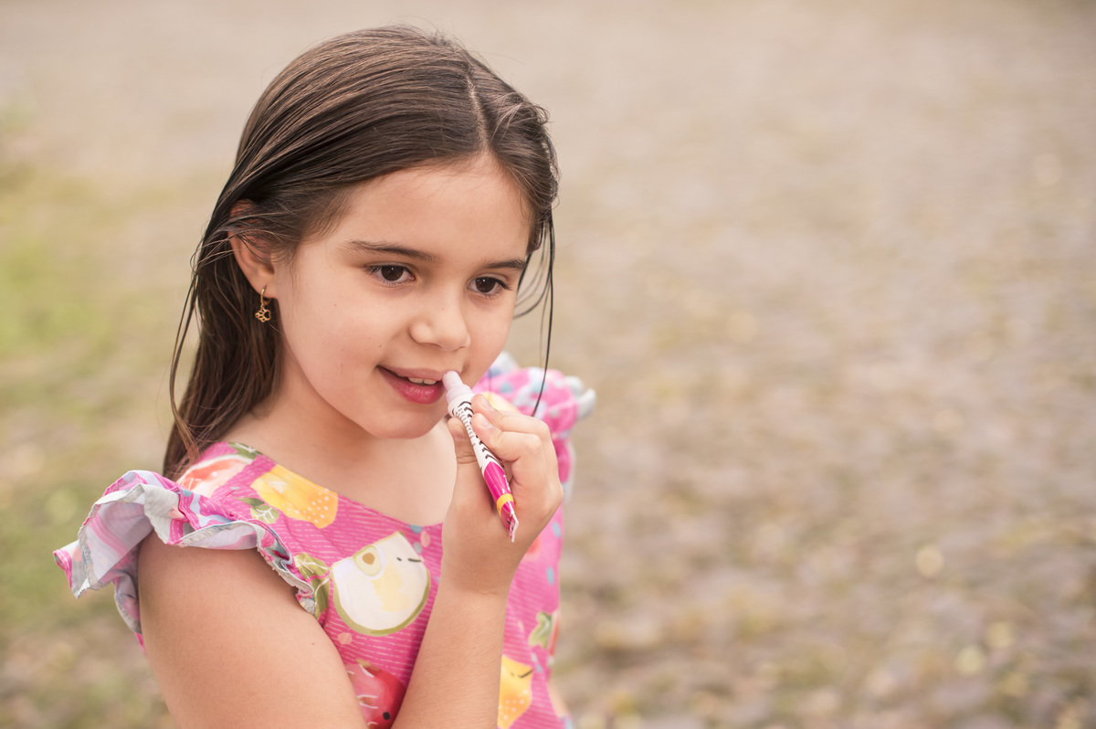 Ensaio externo, menina colocando batom
