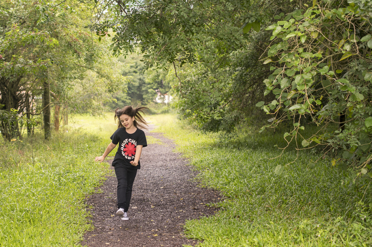 ensaio externo, menina correndo feliz num caminho verde