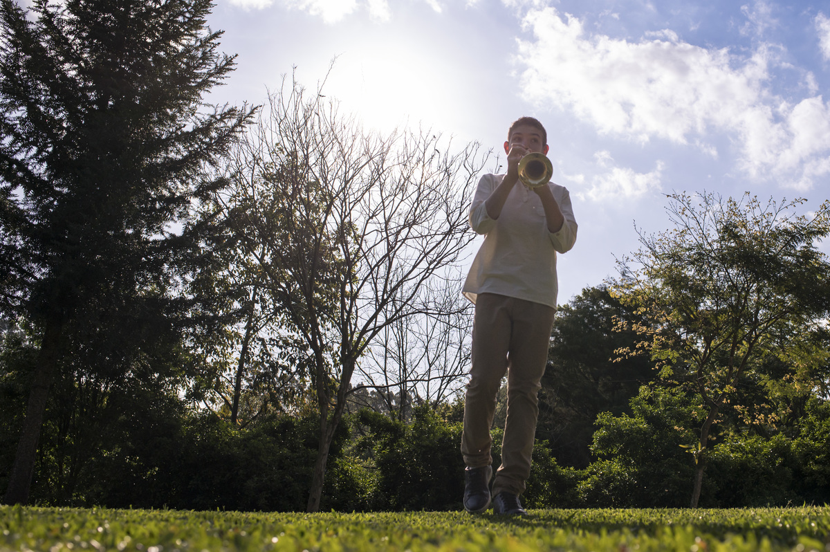 Ensaio externo de família em casa, menino tocando trompete