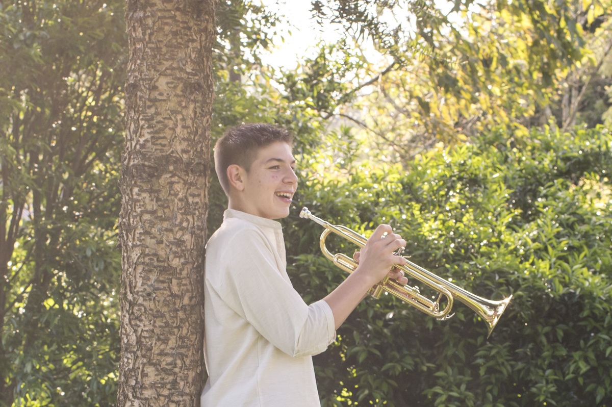Ensaio externo de família em casa, menino sorrindo com trompete