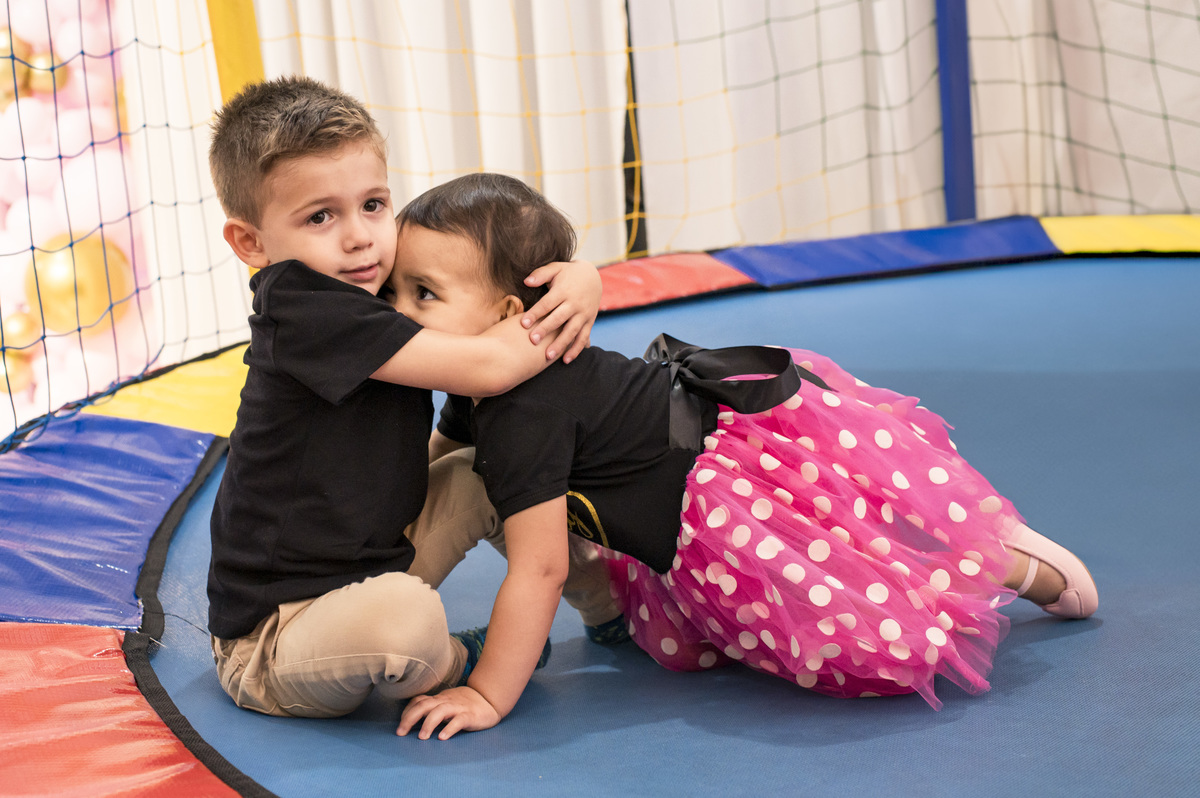Festa de aniversário infantil - amigos trocando abraço na cama elástica