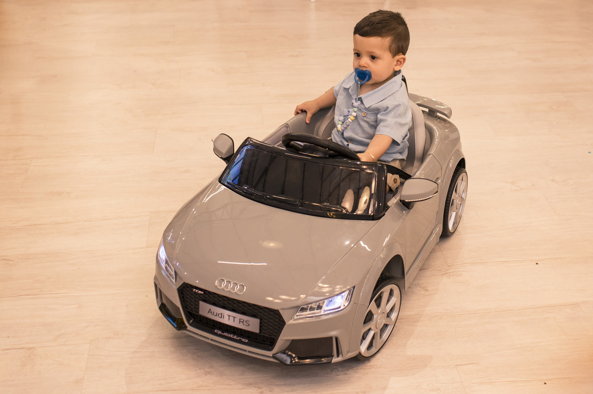 Festa de aniversário infantil, criança andando no seu carrão elétrico