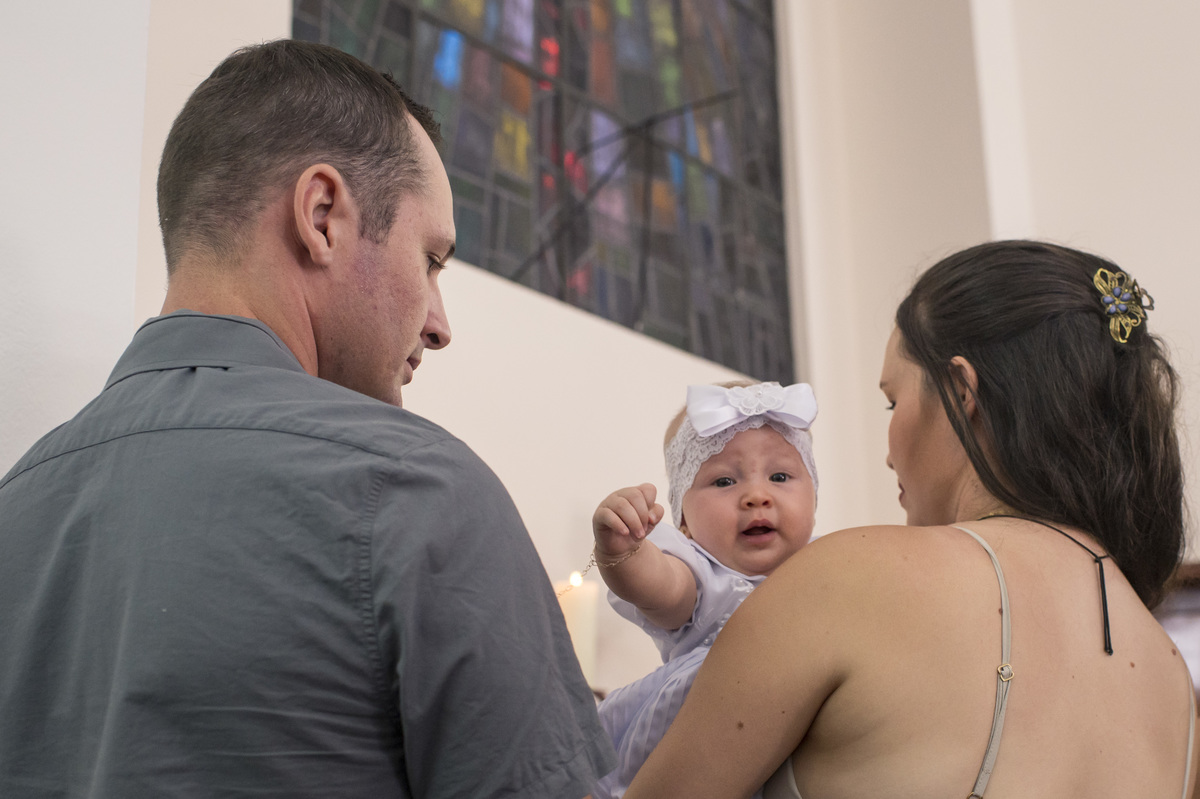 criança no colo dos pais no dia do batizado
