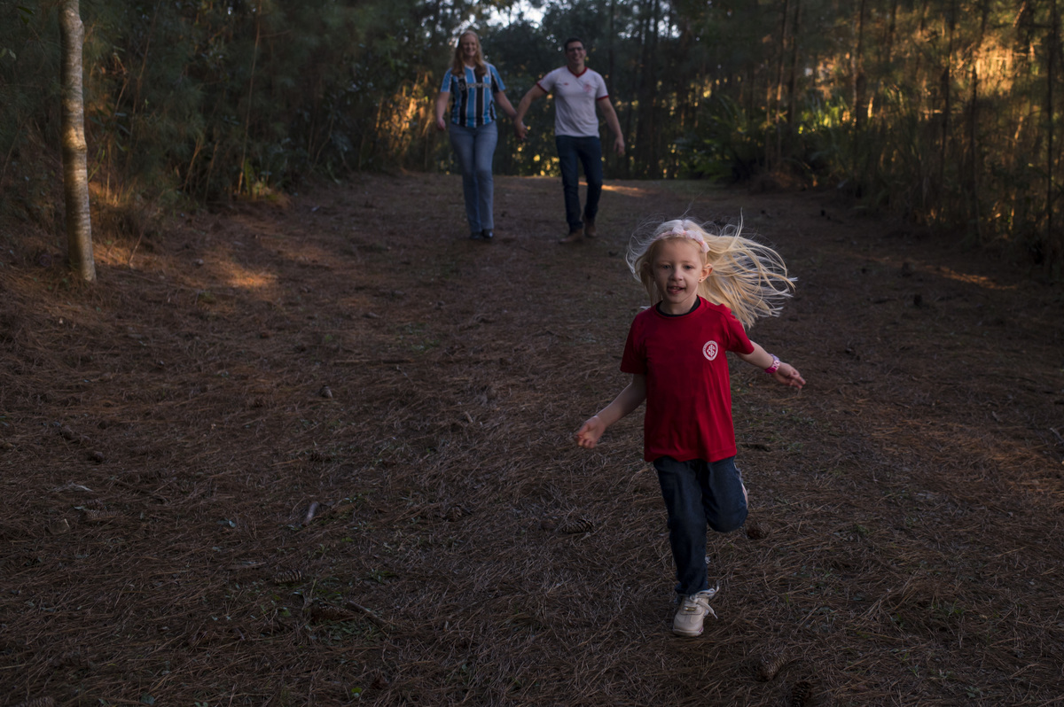 Ensaio externo de família, dupla grenal, menina correndo com camisa do inter, mãe com camiseta do grêmio