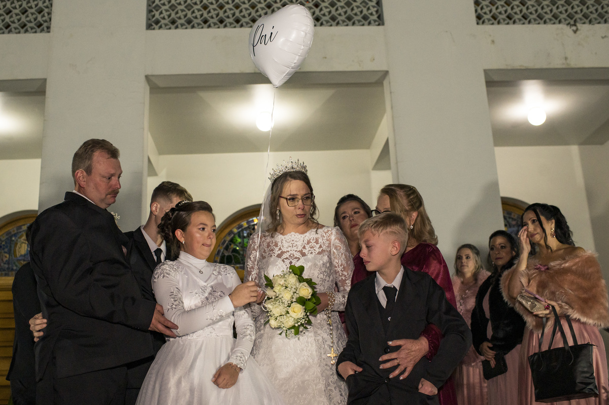 Foto de casamento, noiva e familiares emocionados com homenagem ao pai da noiva, representando por um balão
