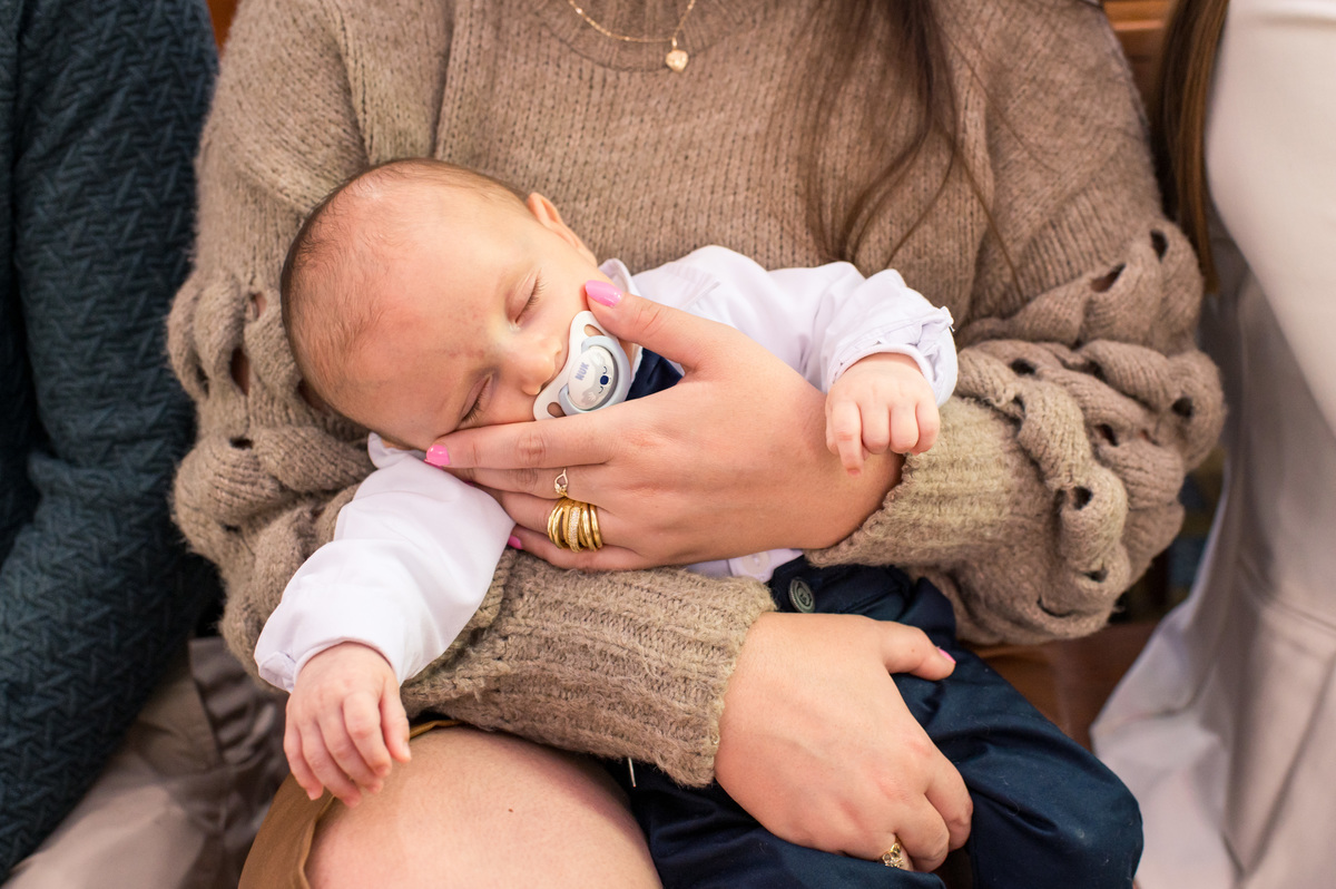 bebê batizado dorme no colo da madrinha