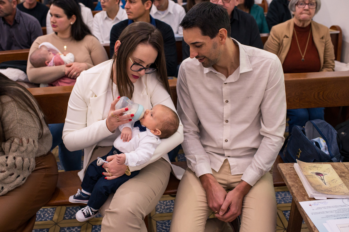 bebê batizado recebendo mamadeira no colo da mãe no banco da igreja da comunidade evangélica de campo do meio