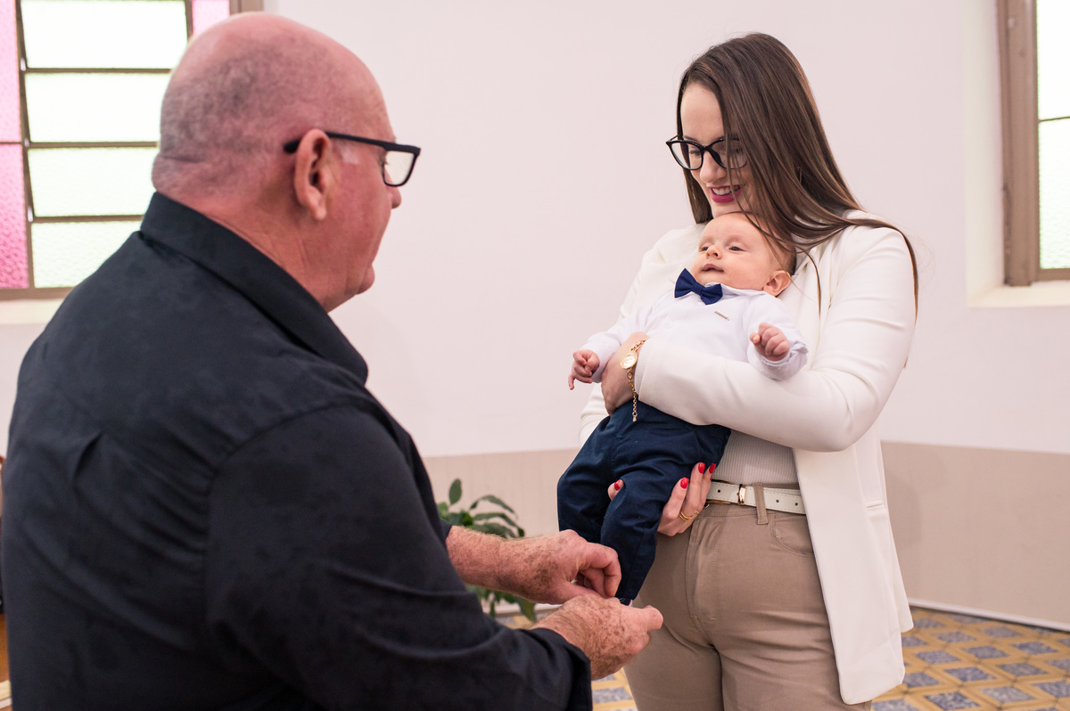avô amarrando o tênis do bebê no batizado