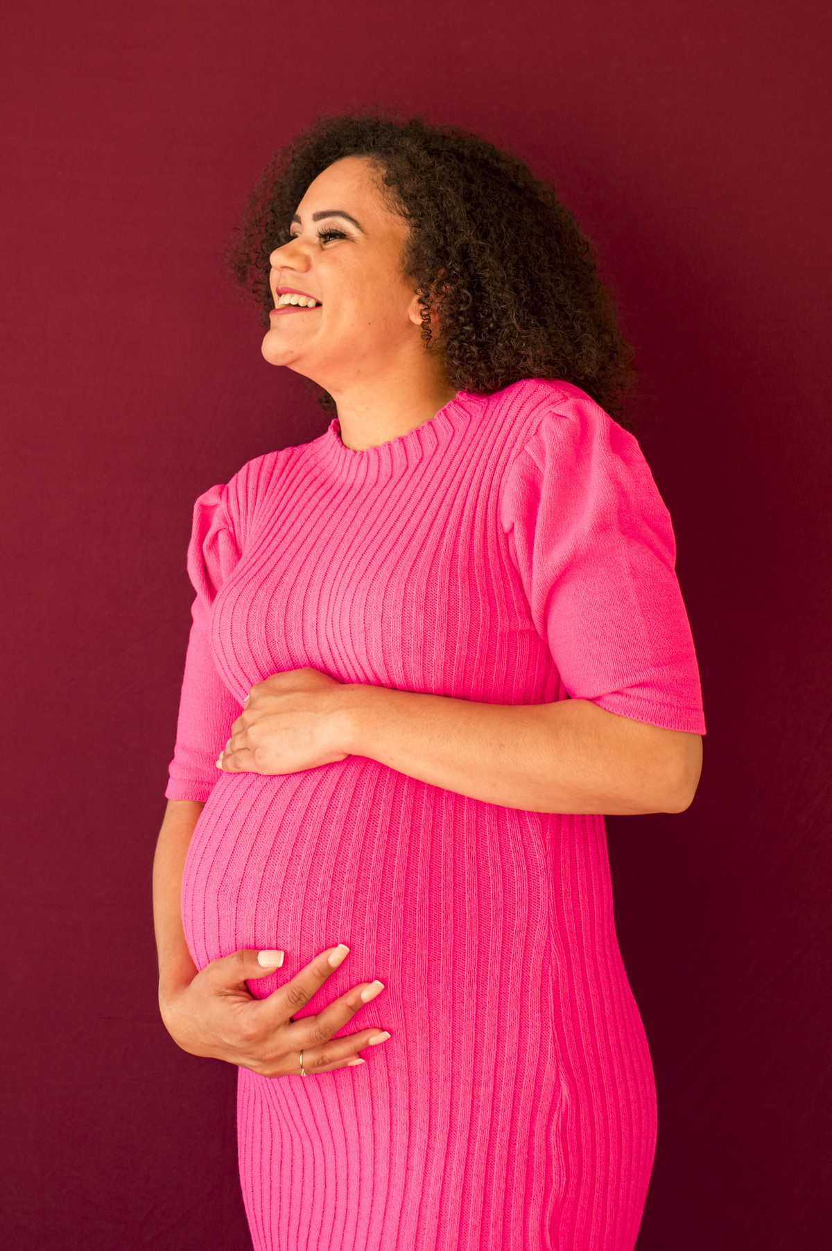 Ensaio fotográfico de gestante em estúdio, mãe abraçando a barriga