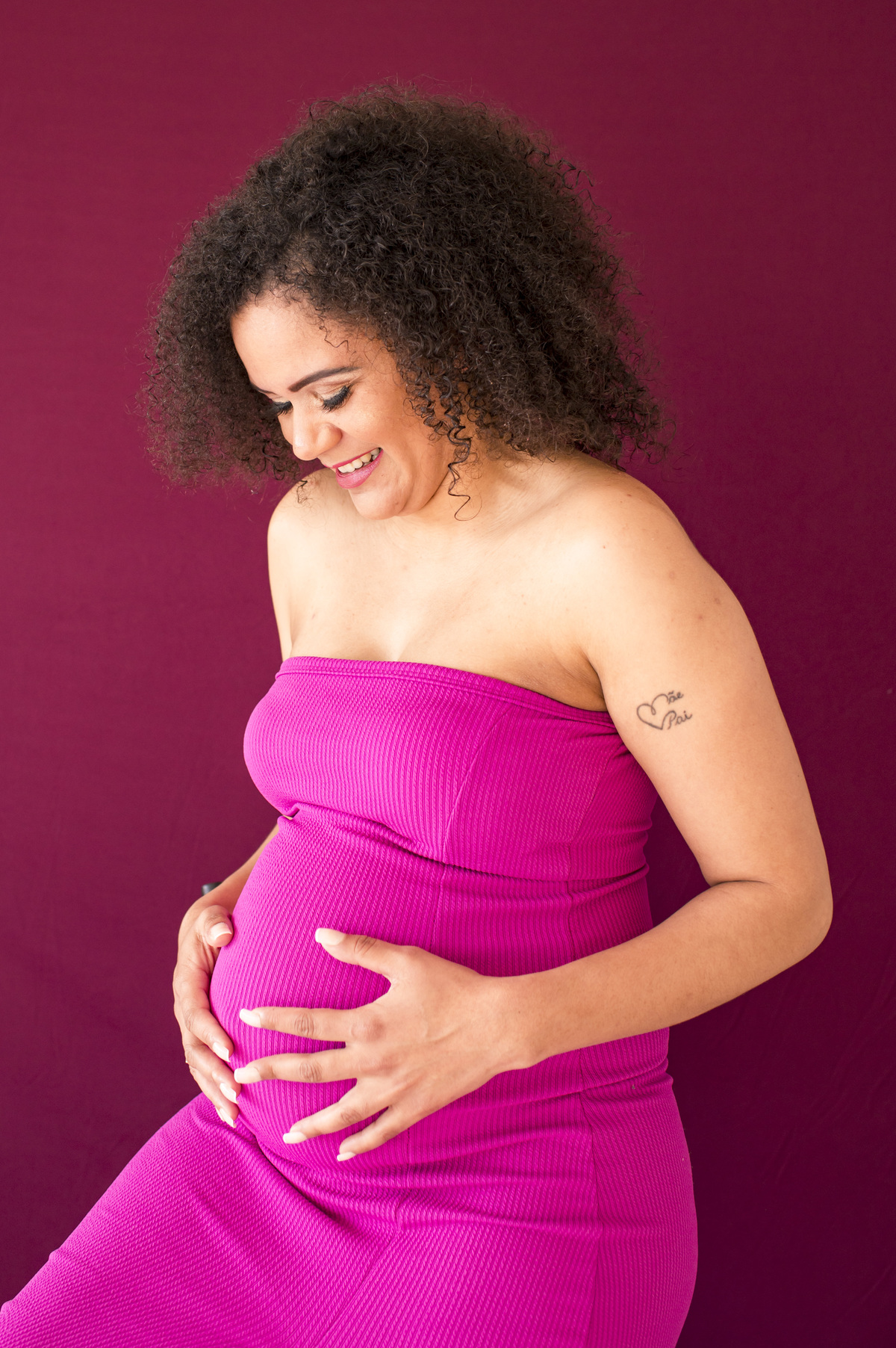 Ensaio fotográfico de gestante em estúdio, mãe fazendo carinho na barriga