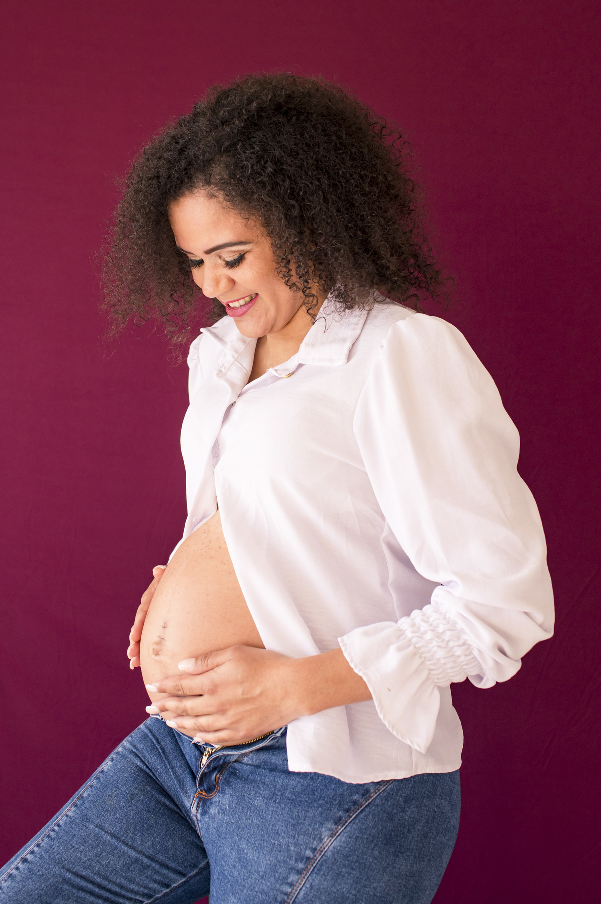 Ensaio fotográfico de gestante em estúdio, foto da gestante fazendo carinho na barriga