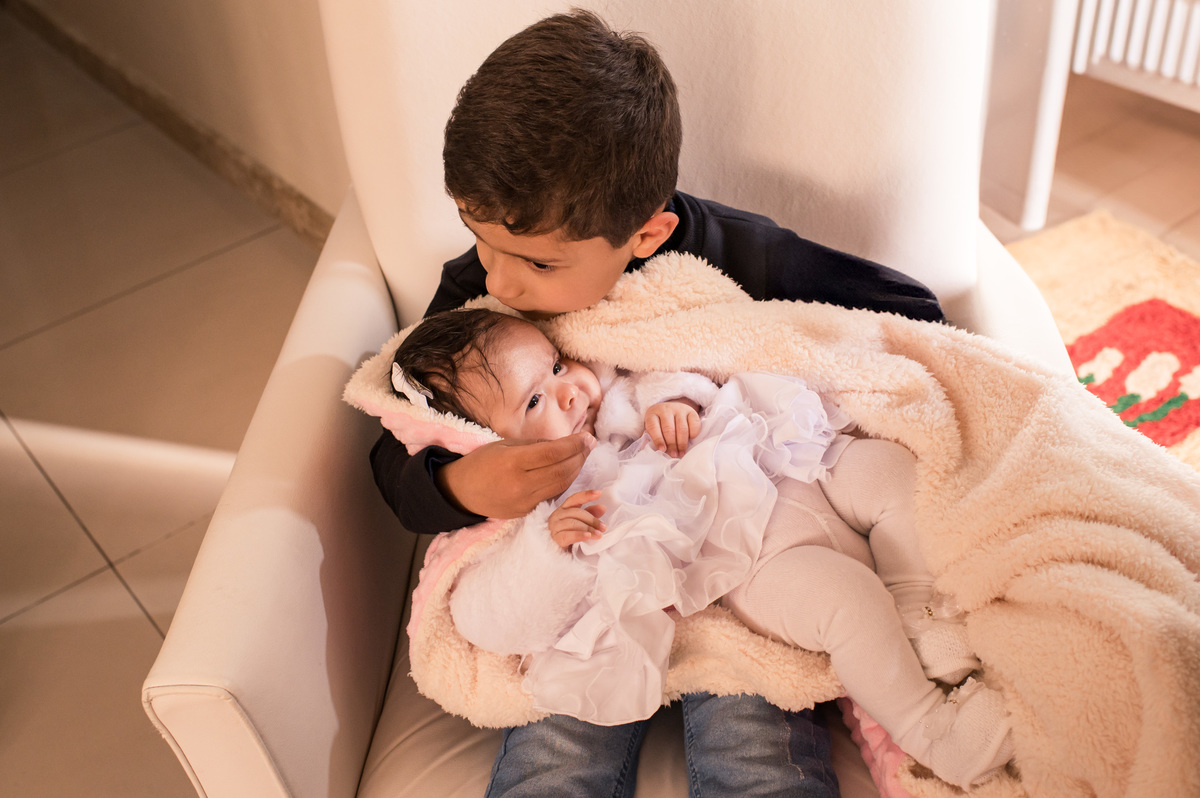 Batizado em São José do Sul, bebê em casa, no colo do irmão