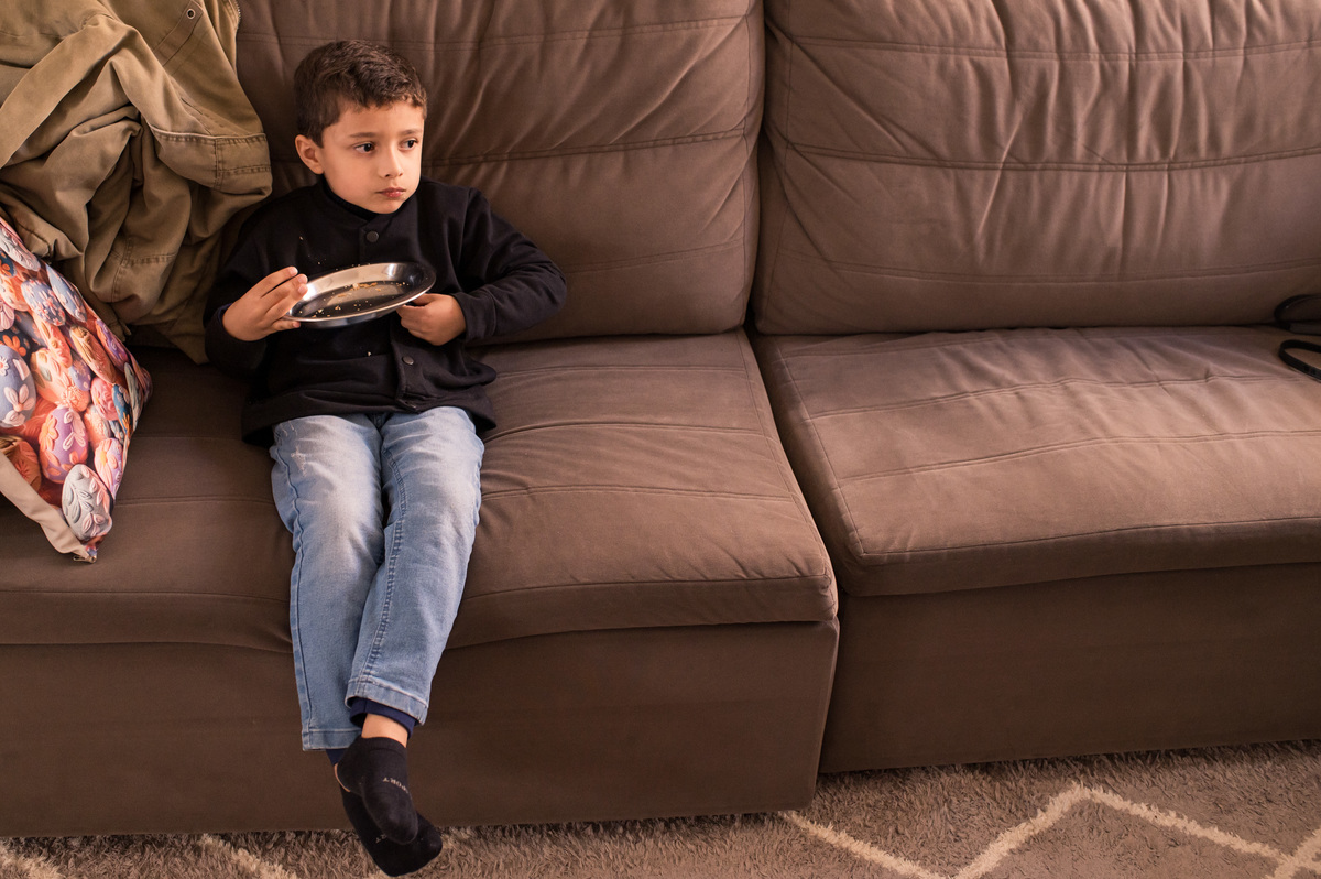 Batizado em São José do Sul, irmão mais velho comendo no sofá