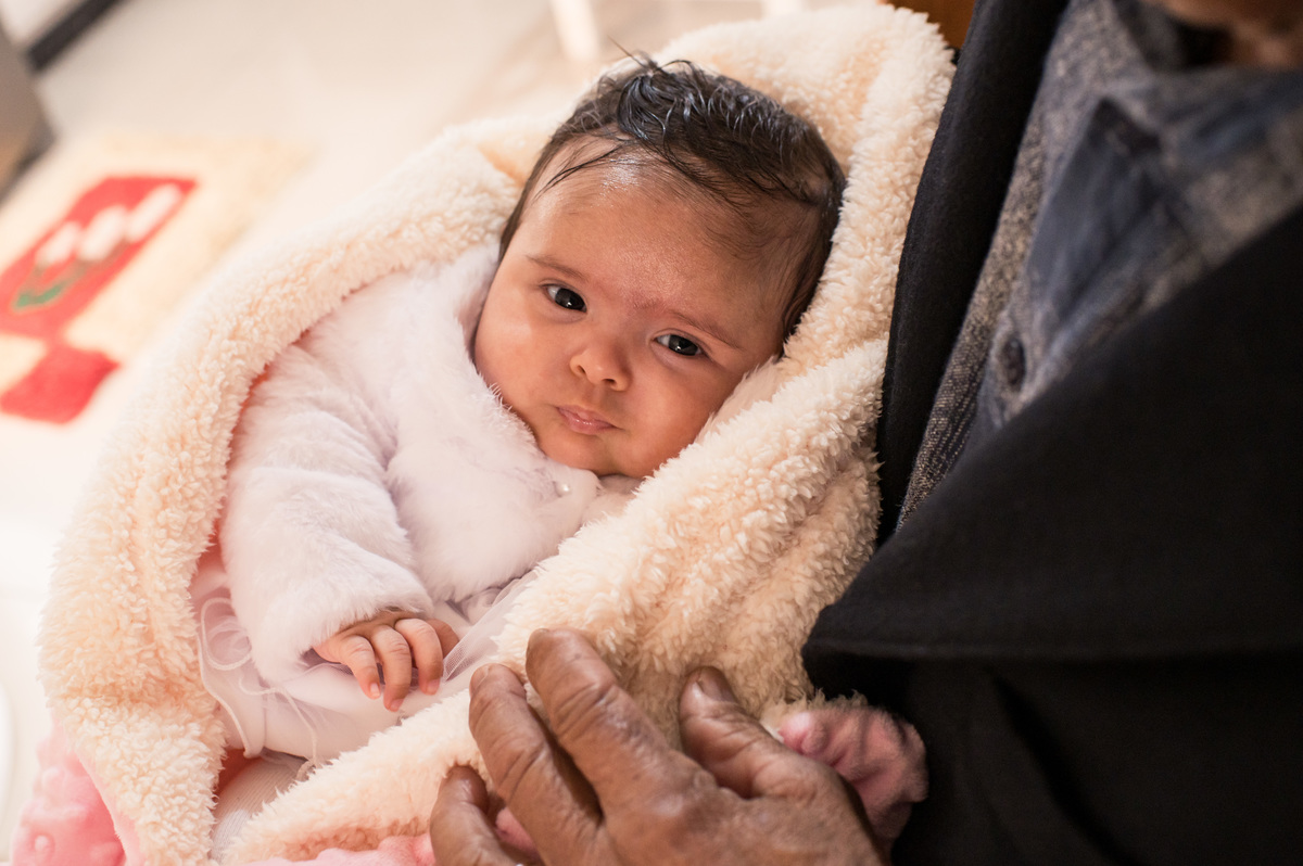 Batizado em São José do Sul, bebê no colo do avô dentro de casa