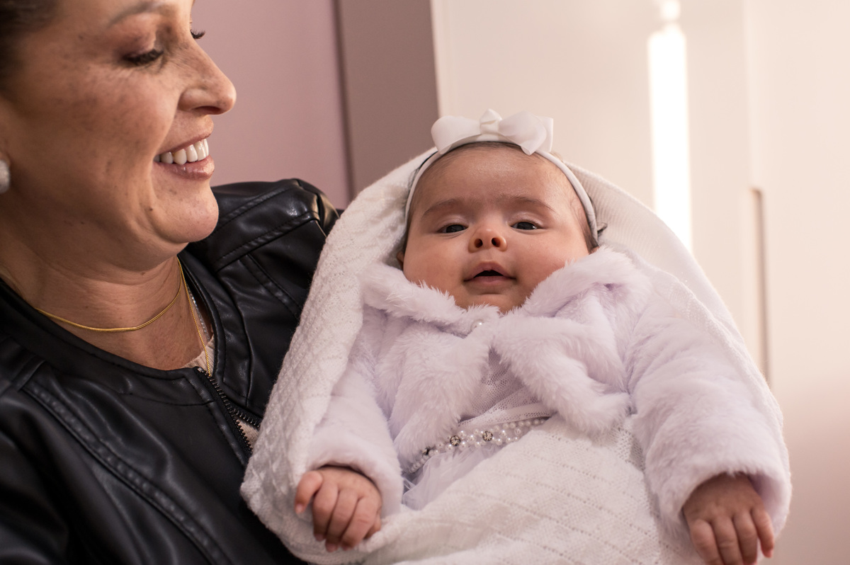 Batizado em São José do Sul, bebê sorrindo no colo da madrinha em casa