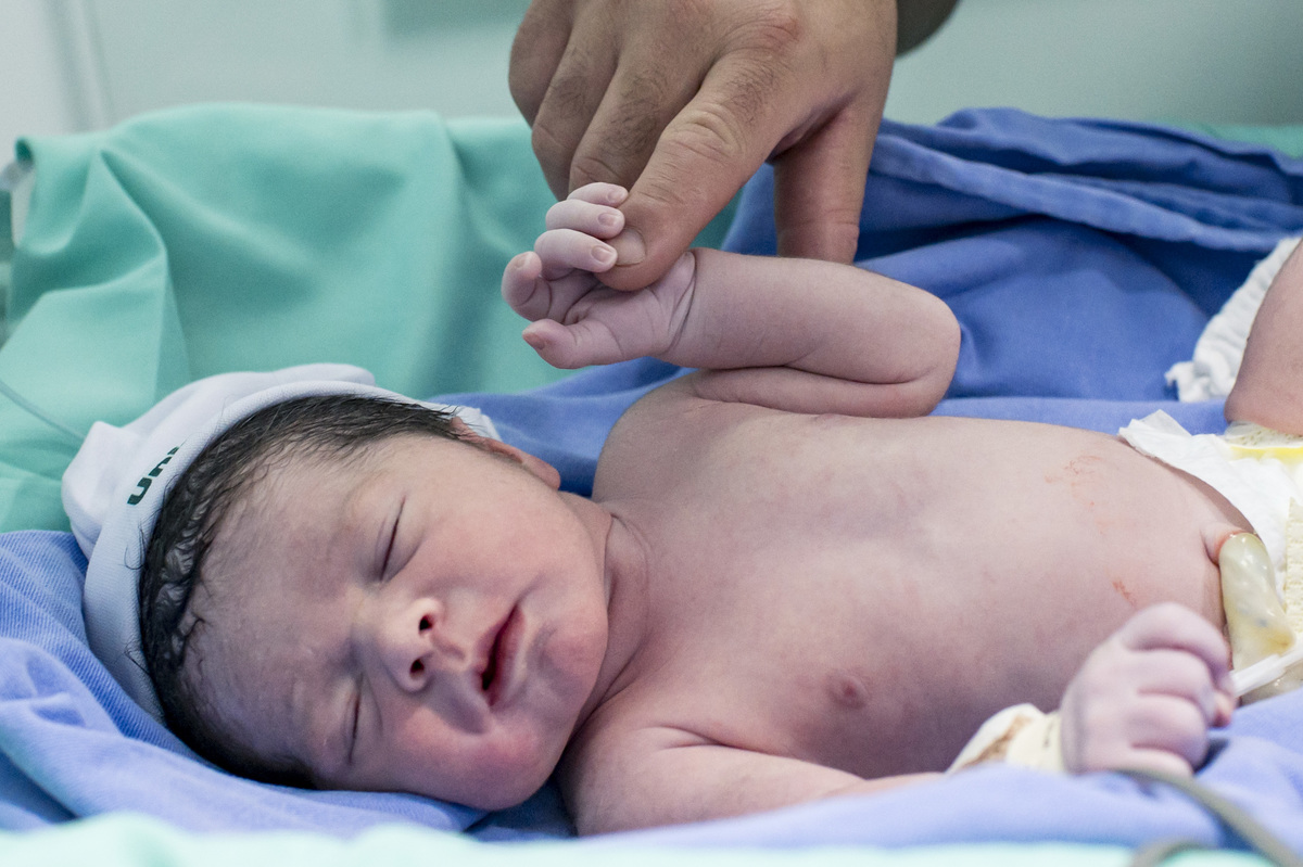 Documental de parto/cesária no hospital Unimed Vale do Caí, pai dando a mão para o bebê