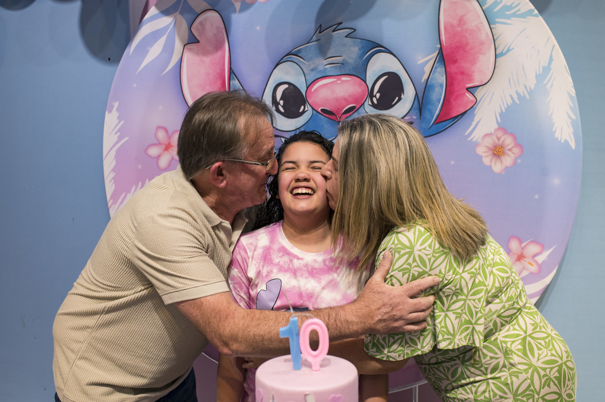 Festa de aniversário infantil - ArfFestas Kids - decoração Lilo e Stitch - fotógrafa Claudia Wallauer, aniversariante recebendo carinho dos pais na mesa decorada