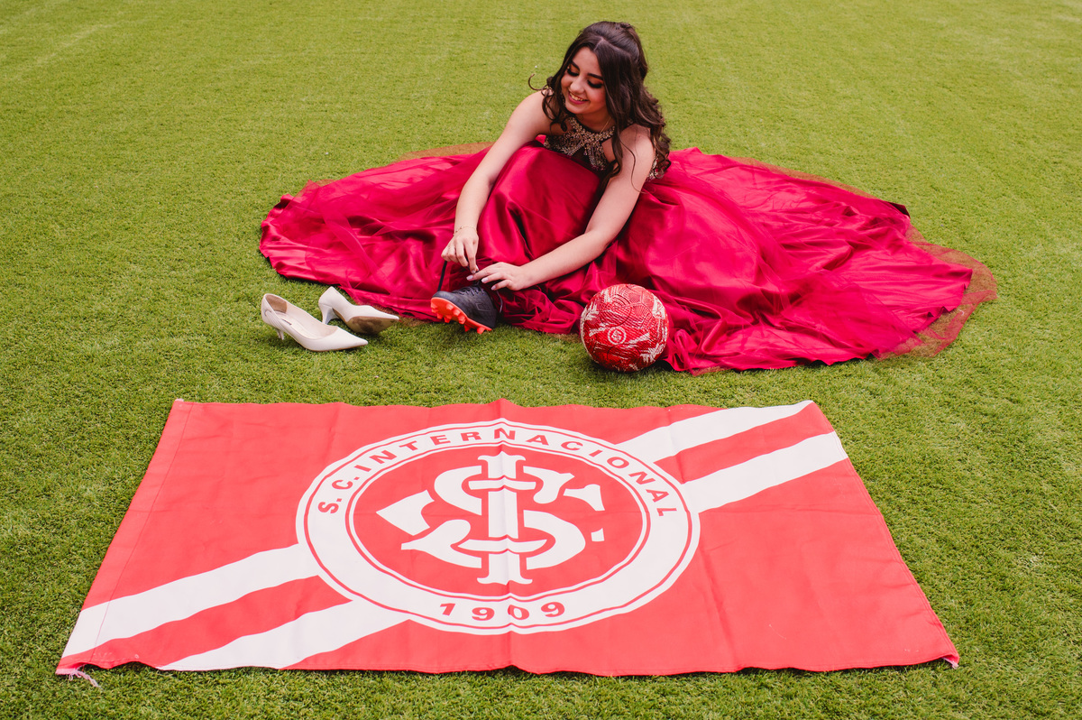 Ensaio fotográfico pré 15 anos no estádio Beira Rio - fotógrafa Claudia Wallauer - debutante colocando uma chuteira
