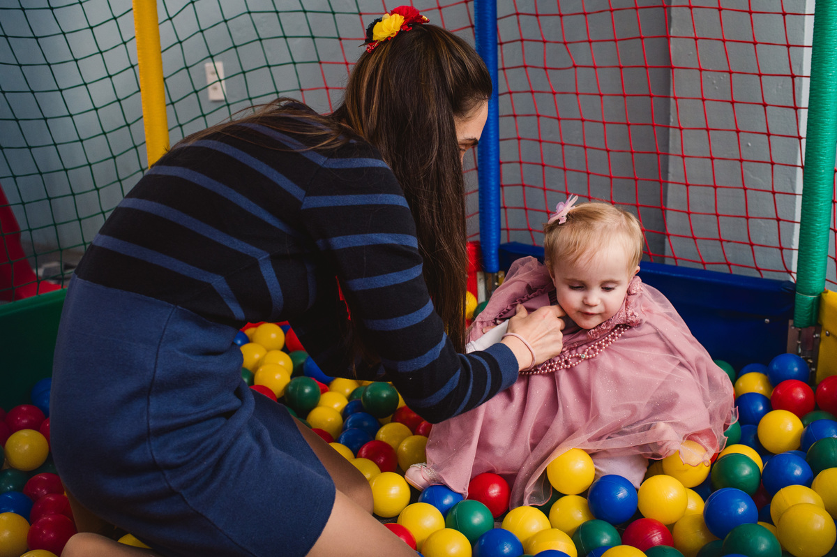 Festa de aniversário infantil em Brochier, fotógrafa Claudia Wallauer, mãe colocando o vestido na criança, dentro da piscina de bolinhas