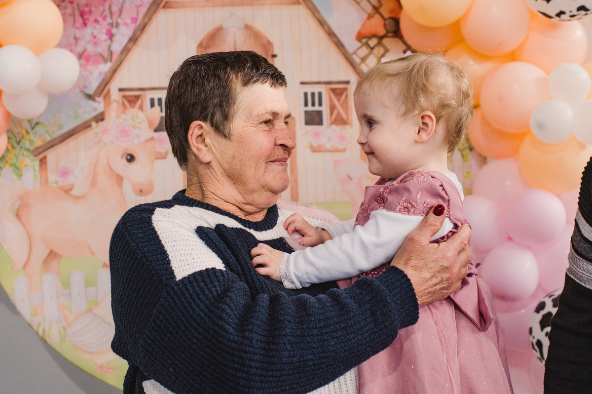 Festa de aniversário infantil em Brochier, fotógrafa Claudia Wallauer, criança olhando para a vovó, na decoração de fazendinha