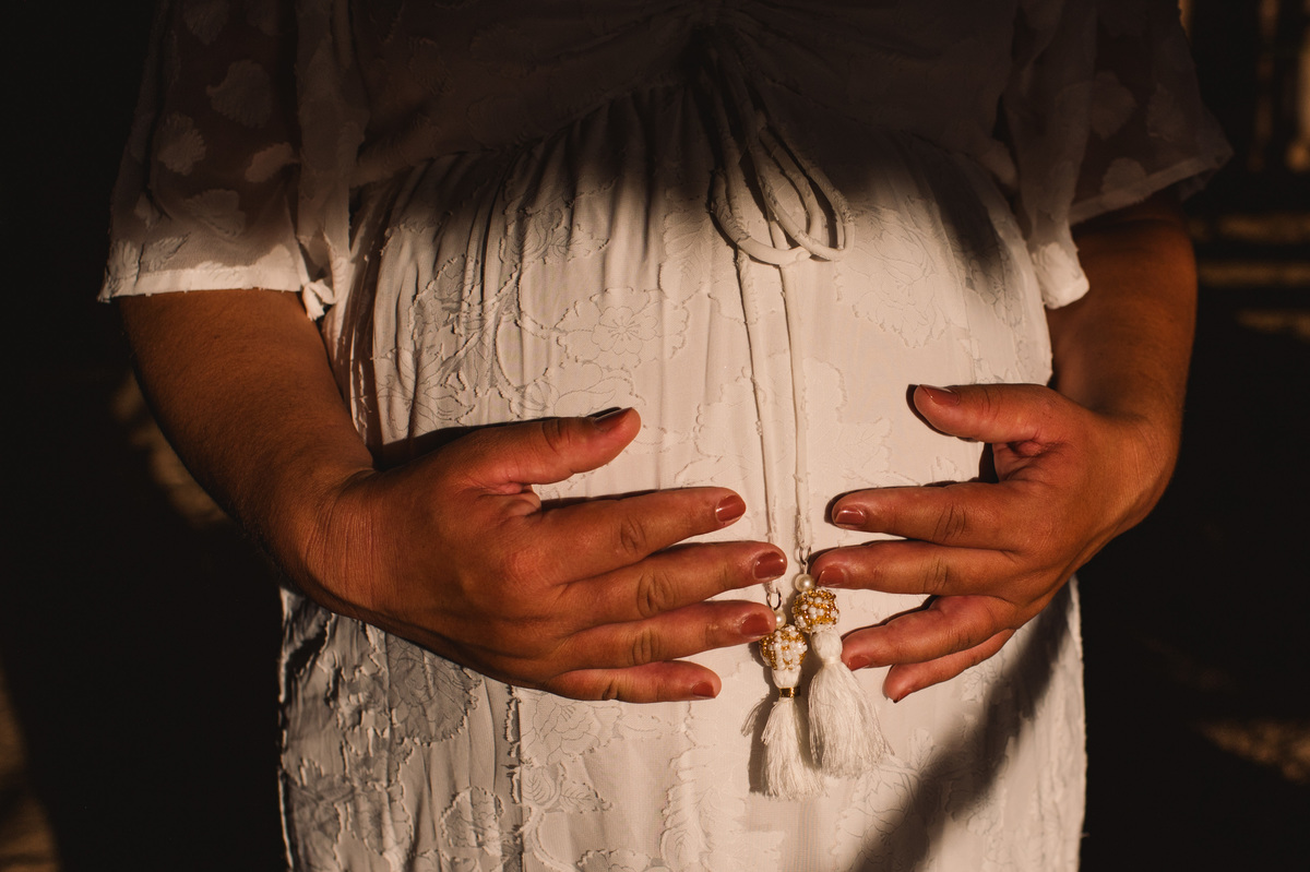 Ensaio gestante na chácara, foto da barriga bem de perto, com a luz do sol