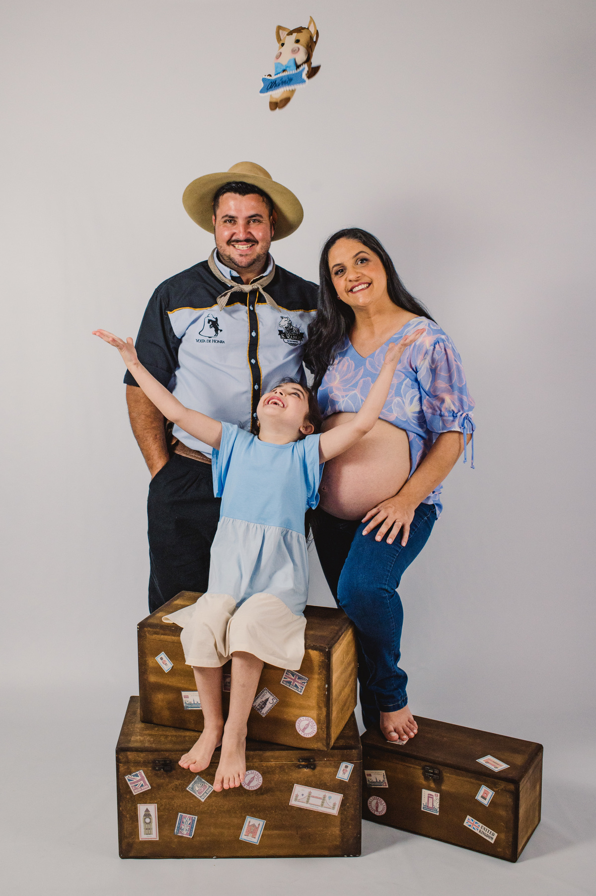 Ensaio de gestante em estúdio, tocando cavalinho de pelúcia para o alto