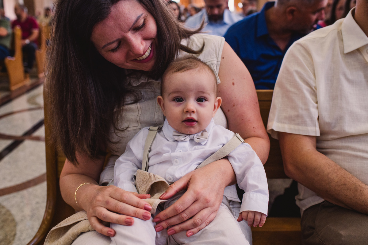 Fotos de batismo na Catedral de Montenegro - Fotógrafa Claudia Wallauer - criança no colo da mãe durante a missa