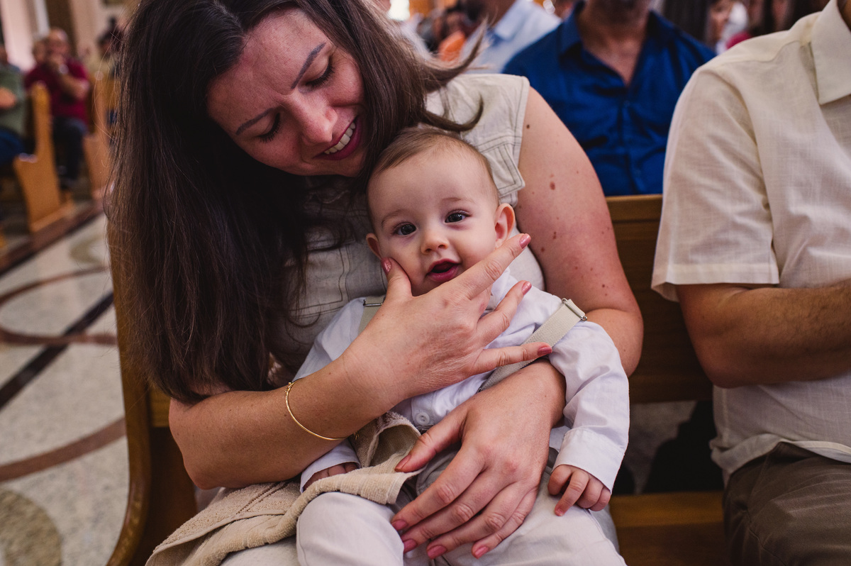 Fotos de batismo na Catedral de Montenegro - Fotógrafa Claudia Wallauer - criança recebendo carinho da mãe durante a missa