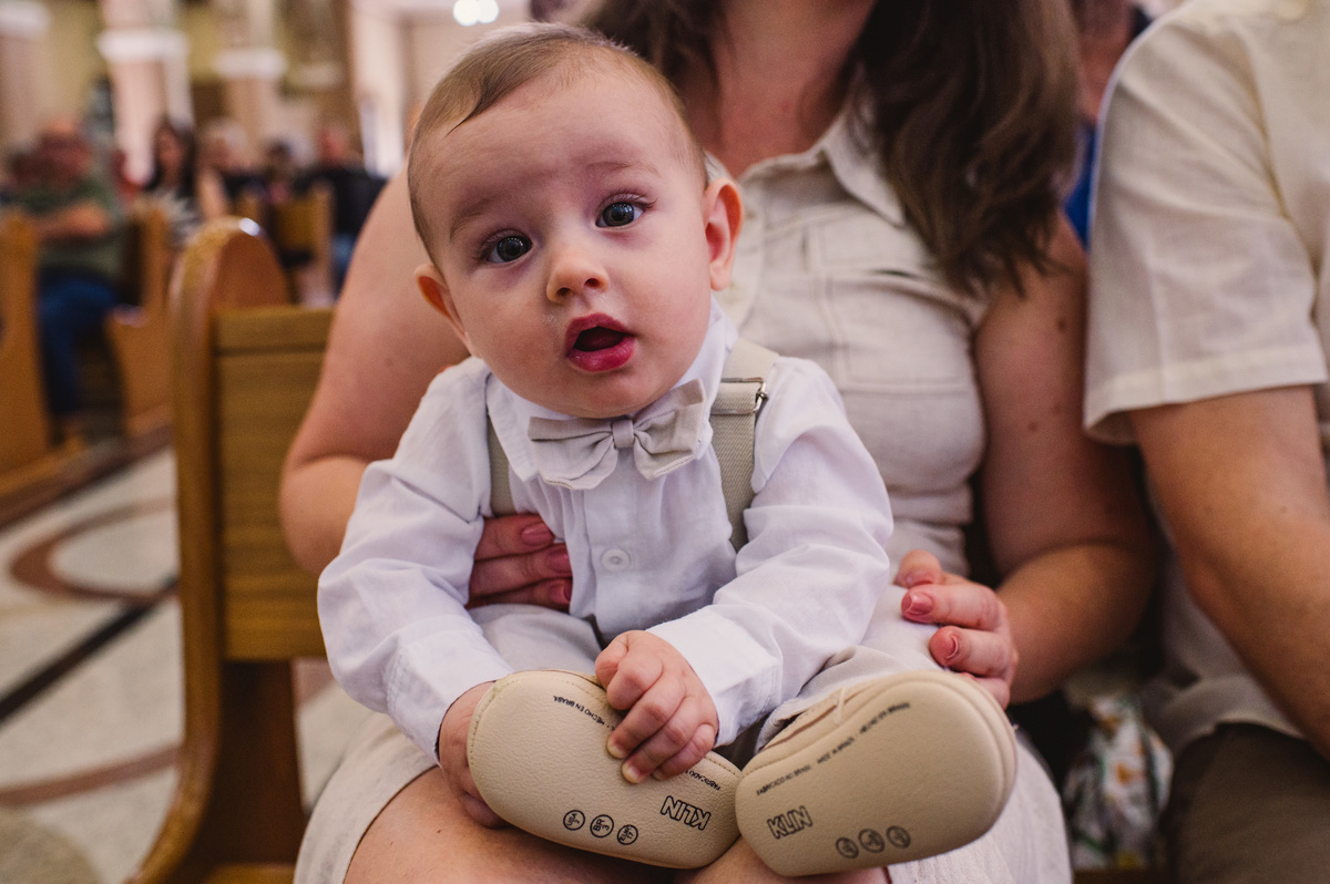 Fotos de batismo na Catedral de Montenegro - Fotógrafa Claudia Wallauer - criança no colo da mãe durante a missa