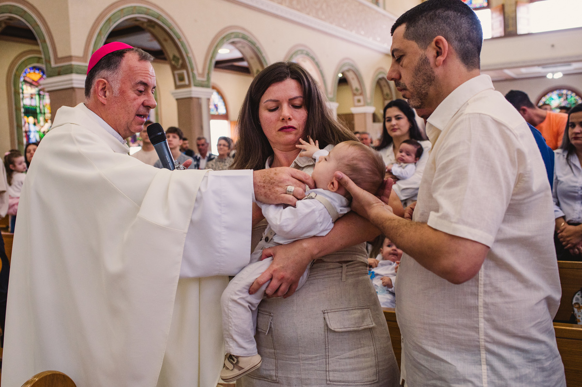 Fotos de batismo na Catedral de Montenegro - Fotógrafa Claudia Wallauer - criança recebendo óleo do padre